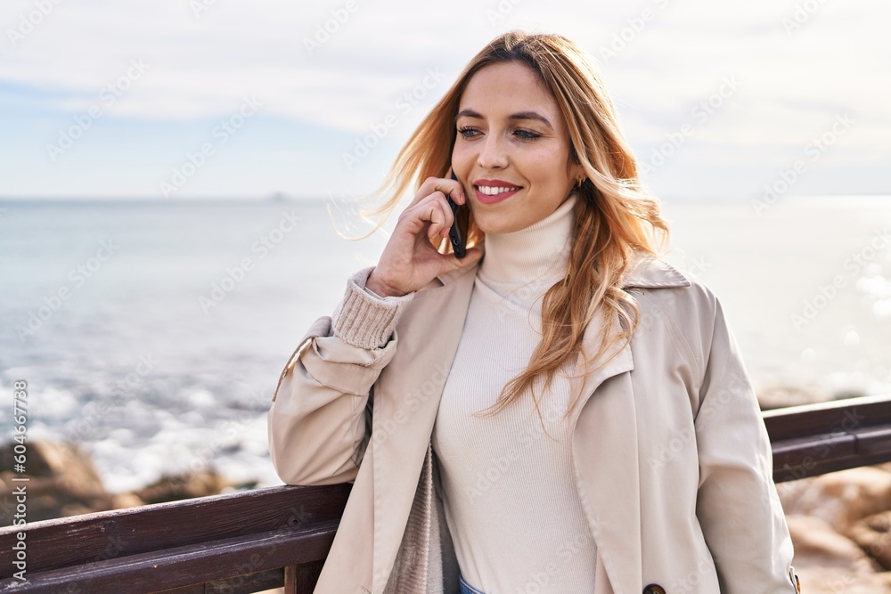 Young blonde woman smiling confident talking on smartphone at seaside Young blonde woman smiling confident talking on smartphone at seaside