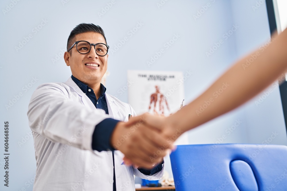 Obraz premium Young latin man pysiotherapist shake hand with patient at rehab clinic