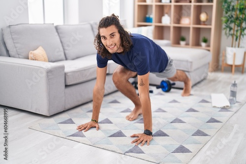 Young hispanic man smiling confident training yoga at home