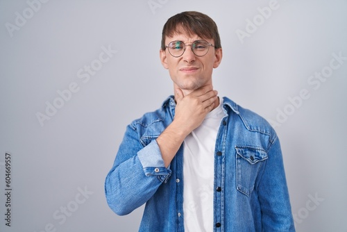 Caucasian blond man standing wearing glasses touching painful neck, sore throat for flu, clod and infection