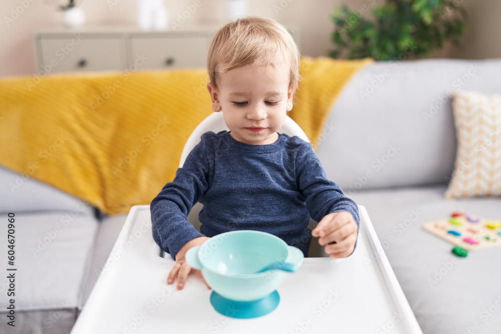 Adorable blond toddler sitting on highchair waiting to eat at home Adorable blond toddler sitting on highchair waiting to eat at home