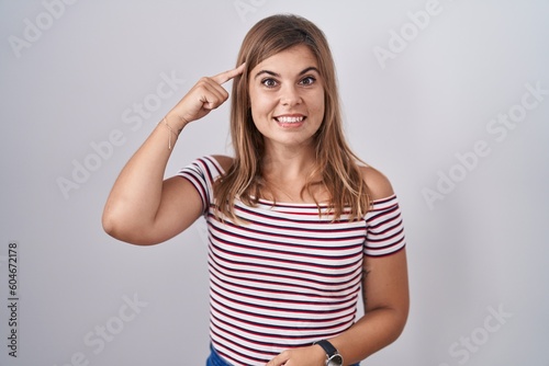 Young hispanic woman standing over isolated background smiling pointing to head with one finger, great idea or thought, good memory