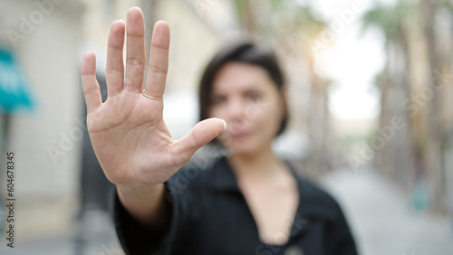 Young caucasian woman doing stop gesture with hand at street