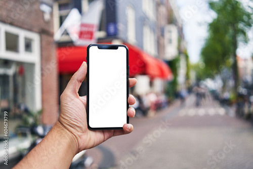 Man holding smartphone showing white blank screen at amsterdam