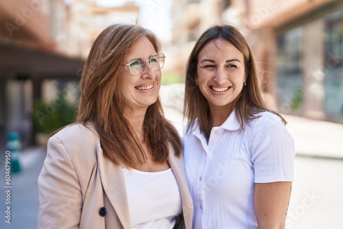 Mother and daughter smiling confident standing together at street