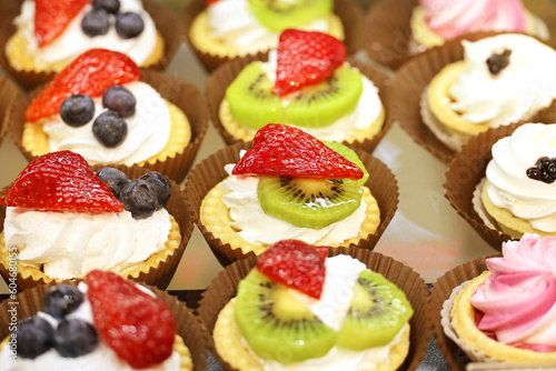 Cakes with fresh fruits and berries, selective focus. Sweet dessert with strawberry, kiwi and blueberries