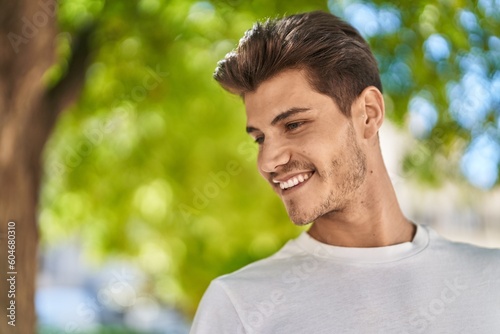 Young hispanic man smiling confident looking to the side at park
