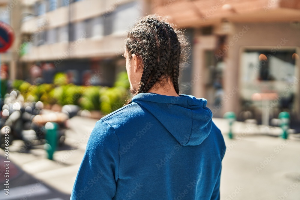 Young man with relaxed expression standing on back view at street