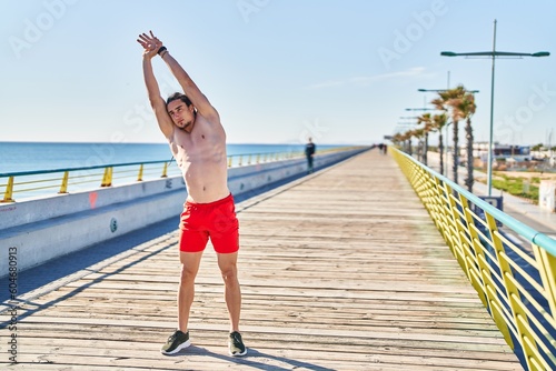 Young man stretching arms at seaside