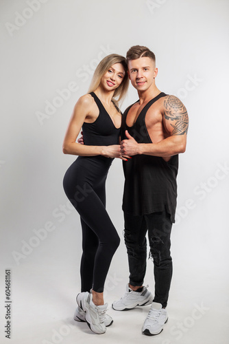 Beautiful sports family. Beautiful young slender fitness lady and handsome athletic muscular man in trendy black sportswear
