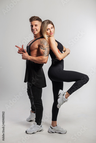 Beautiful happy sports couple in fashionable sportswear on a white background. Handsome muscular man and beautiful fitness lady standing and posing in studio