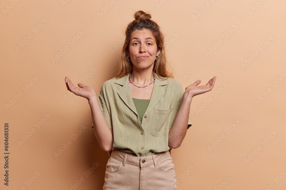 I have no idea. Clueless doubtful young European woman shrugs shoulders and looks questioned or careless dressed in fashionable clothes isolated over brown background. Whats happening I wonder I have no idea. Clueless doubtful young European woman shrugs shoulders and looks questioned or careless dressed in fashionable clothes isolated over brown background. Whats happening I wonder