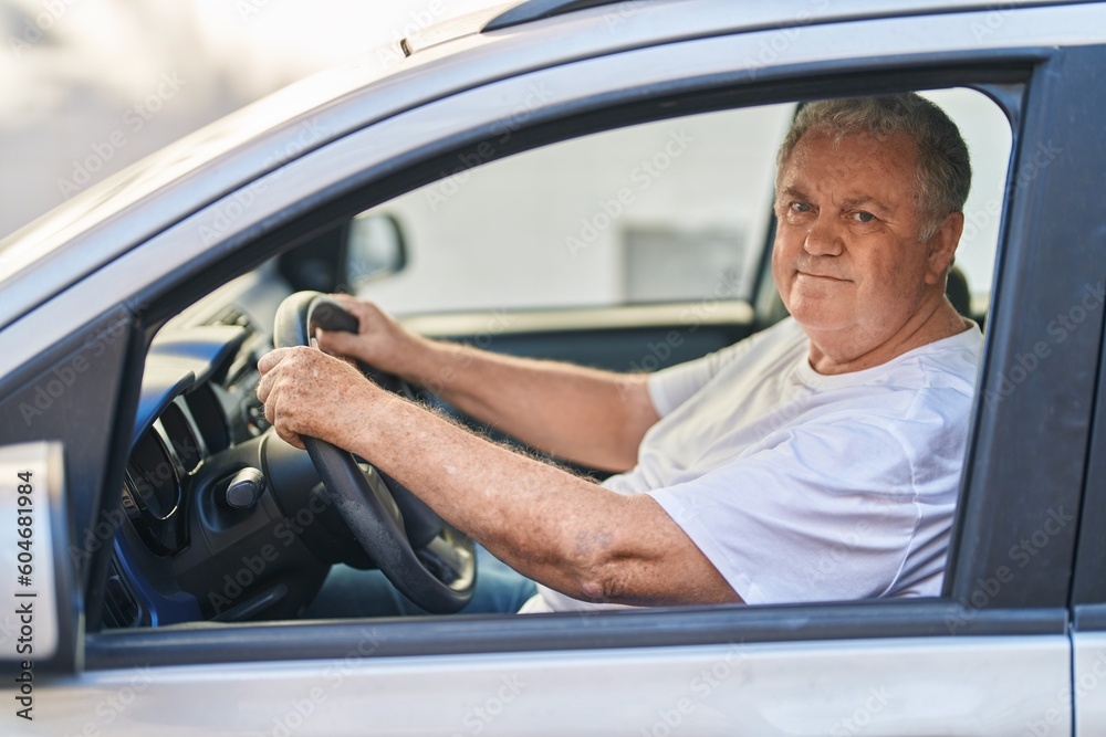 Middle age grey-haired man smiling confident driving car at street