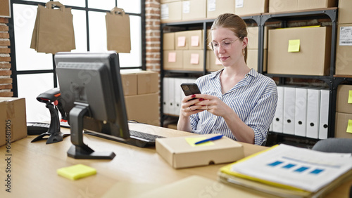 Young blonde woman ecommerce business worker using computer and smartphone at office