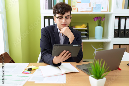 Non binary man business worker using touchpad and laptop at office