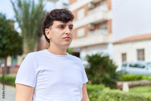 Non binary man standing with serious expression at park