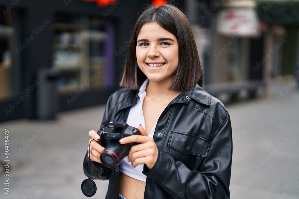 Young beautiful hispanic woman smiling confident using professional camera at street