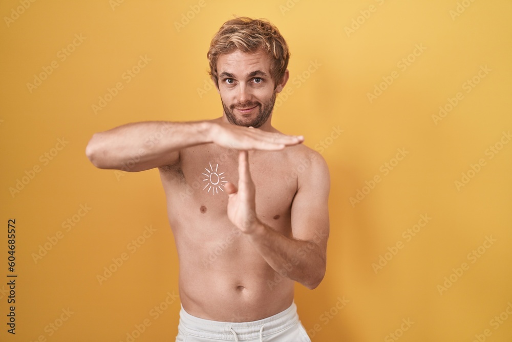 Caucasian man standing shirtless wearing sun screen doing time out gesture with hands, frustrated and serious face