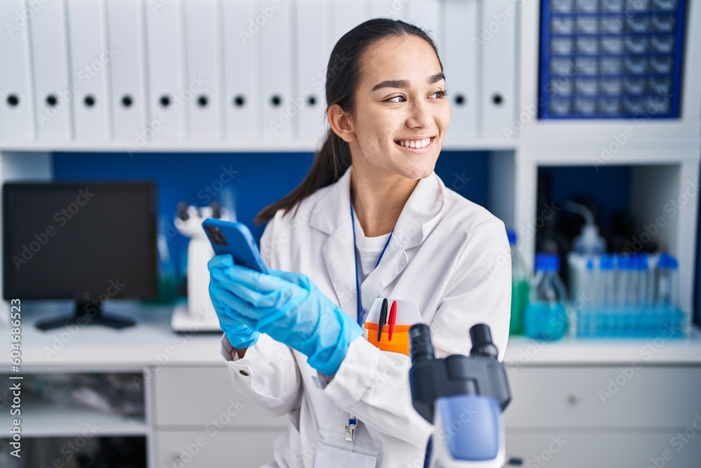 Young hispanic woman scientist using smartphone working at laboratory Young hispanic woman scientist using smartphone working at laboratory