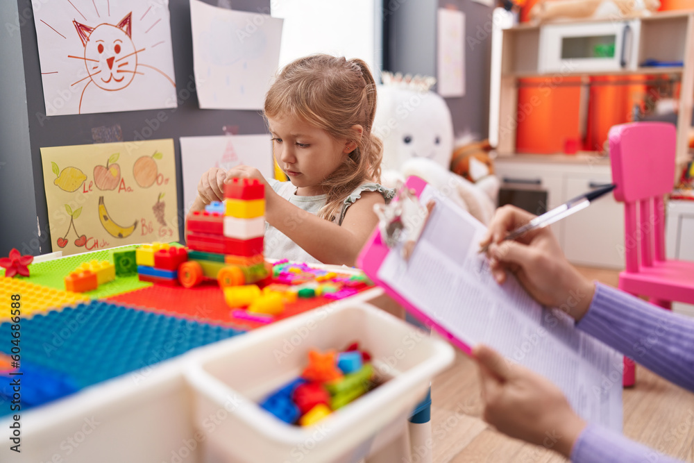 Adorable blonde girl playing with construction blocks having therapy at kindergarten Adorable blonde girl playing with construction blocks having therapy at kindergarten