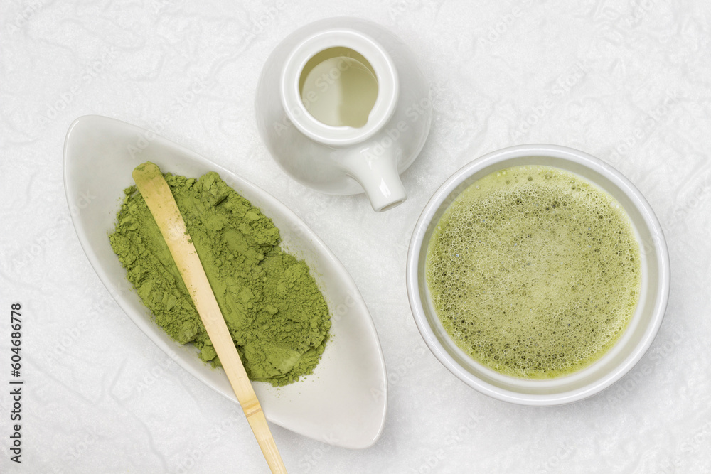 Matcha green tea in a bowl. Bamboo measuring spoon in a bowl of matcha powder. Porcelain milkman with milk. Matcha green tea in a bowl. Bamboo measuring spoon in a bowl of matcha powder. Porcelain milkman with milk.