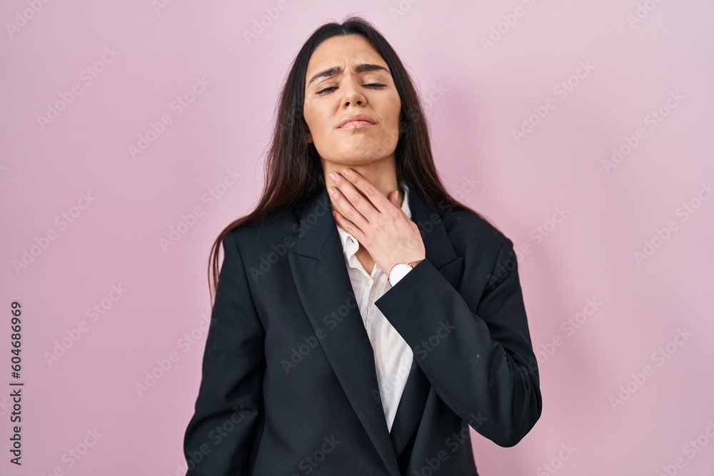 Young brunette woman wearing business style over pink background touching painful neck, sore throat for flu, clod and infection Young brunette woman wearing business style over pink background touching painful neck, sore throat for flu, clod and infection