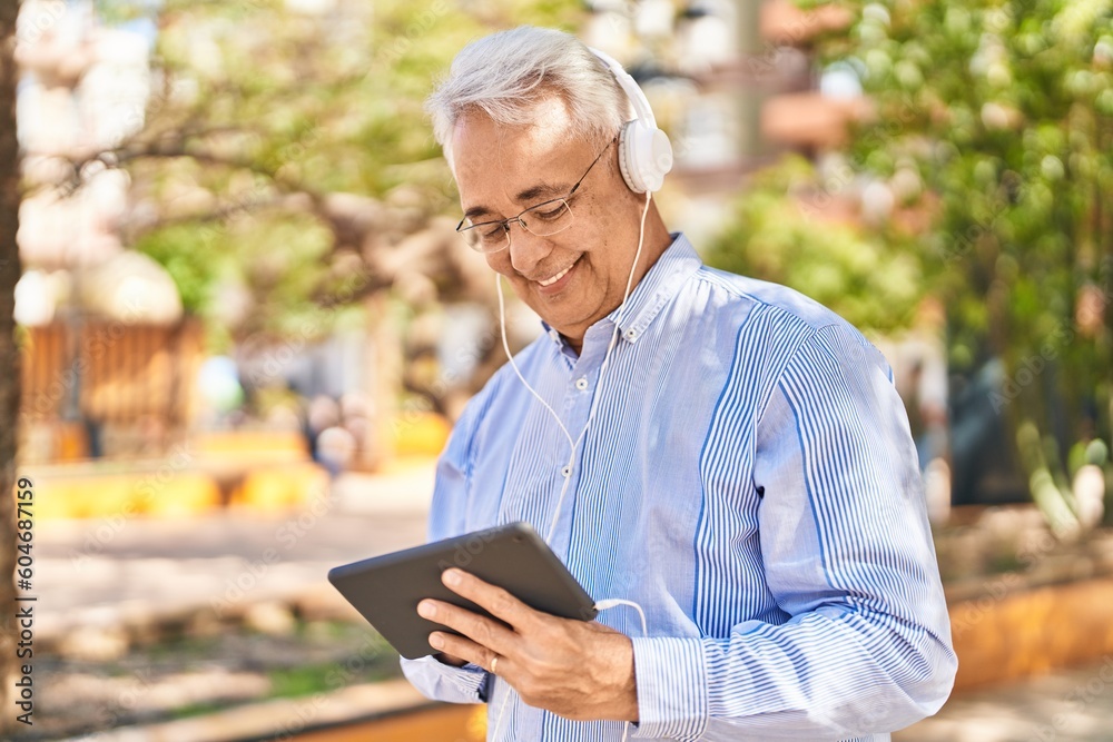 Senior man smiling confident watching video on touchpad at park Senior man smiling confident watching video on touchpad at park