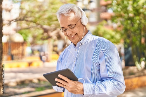 Senior man smiling confident watching video on touchpad at park