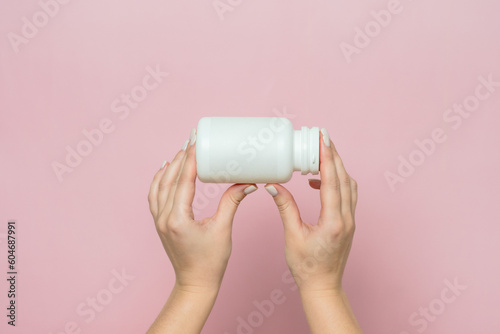 Bottle of pills or vitamins in woman's hand. Product branding mockup.