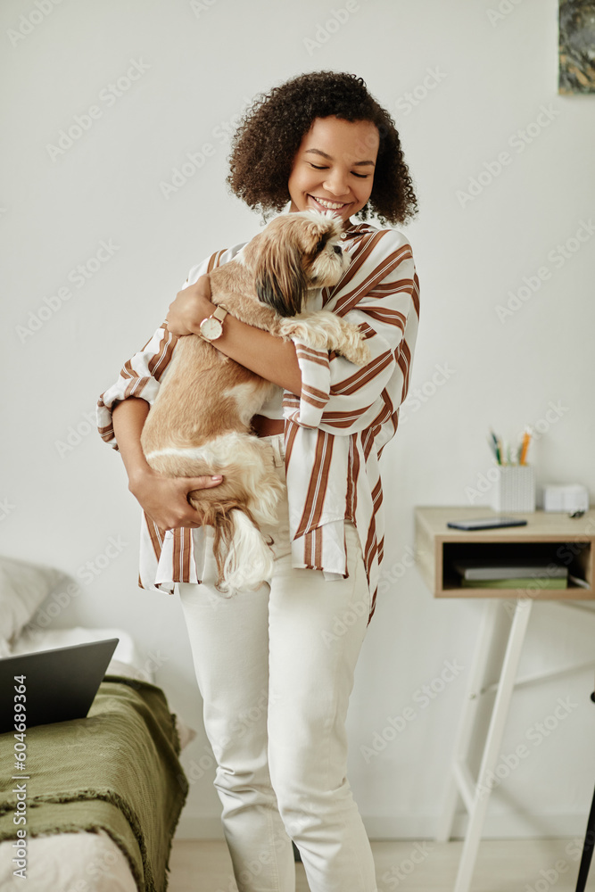 Vertical portrait of black young woman holding little dog at home and smiling happily Vertical portrait of black young woman holding little dog at home and smiling happily
