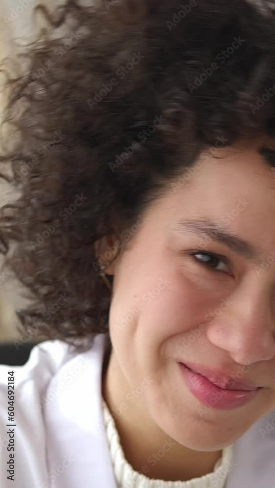 Portrait of happy woman nurse. POV young curly female doctor smiling at camera. Vertical footage. Portrait of happy woman nurse. POV young curly female doctor smiling at camera. Vertical footage.