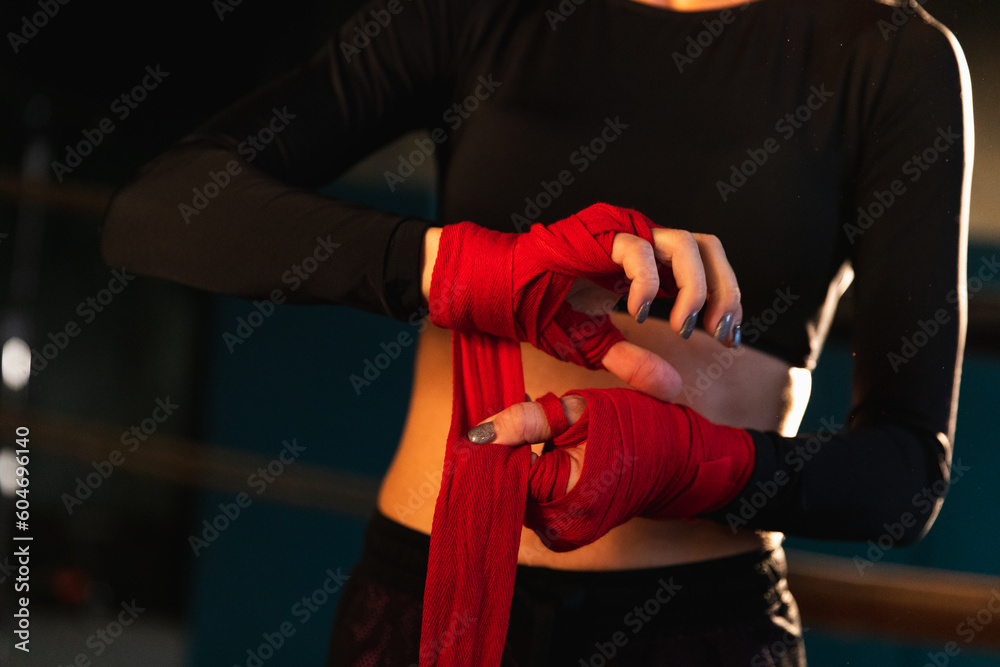 Women self defense girl power. Woman fighter preparing for fight wrapping hands with red boxing wraps sports protective bandages. Strong hands ready for fight active exercise sparring workout training