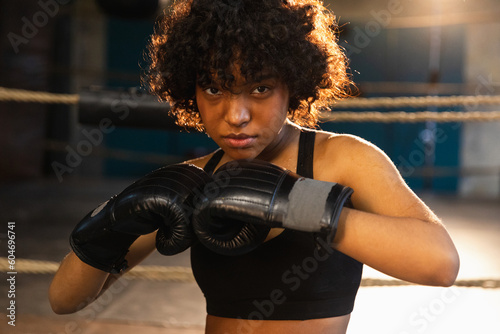 Outcry independent girl power. Angry african american woman fighter with boxing gloves looking serious aggressive standing on boxing ring. Strong powerful fighter girl training punches © Юлия Завалишина