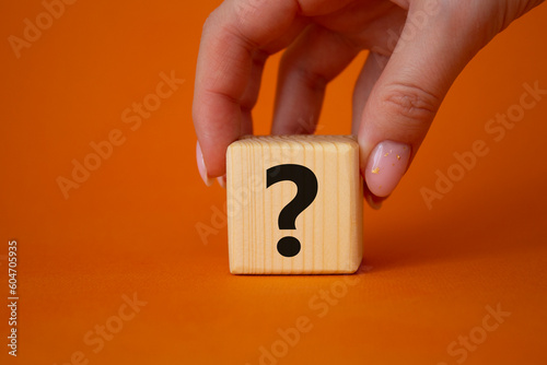 Question mark symbol. Concept words question mark on wooden cube. Businessman hand. Beautiful orange background. Business and question mark. Copy space.