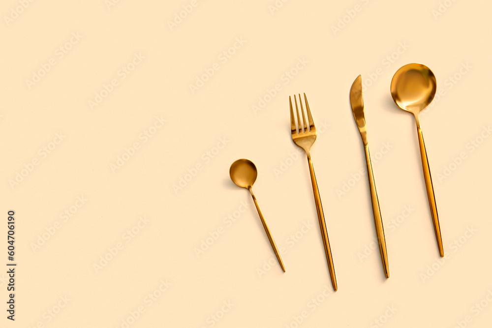 Golden cutlery on beige background Golden cutlery on beige background