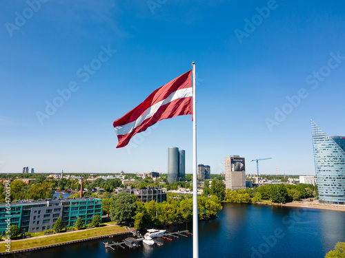 Huge Latvian flag flutters in the wind with Riga in the background in Latvia. Beautiful summer day. photo
