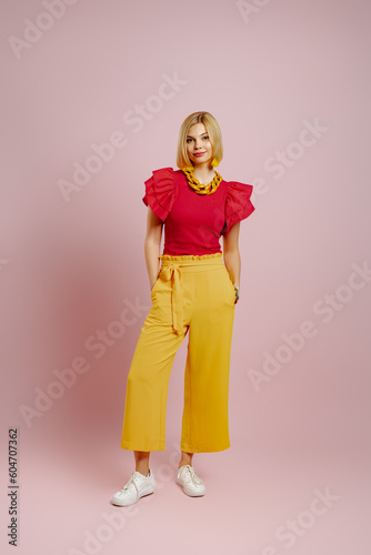 Full length of fashionable young woman standing against colored background