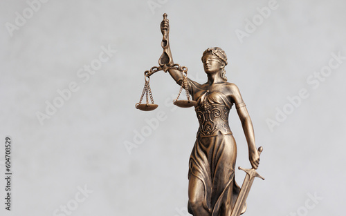 themis goddess of justice statuette on light gray background. symbol of law with scales sword in hands. legal company or university of law and judicial structure. court acquittal of the verdict photo