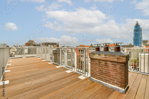 Fototapeta Naklejka Na Ścianę i Meble -  a rooftop with some buildings in the background and a blue sky filled with fluffy white clouds above it, as seen from an apartment