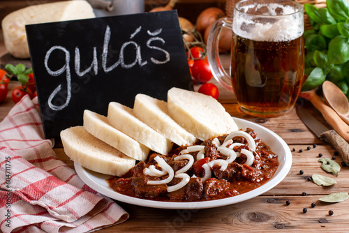 Photography Traditional goulash meat with dumplings (knedliky) on white plate, tomatoes, oni