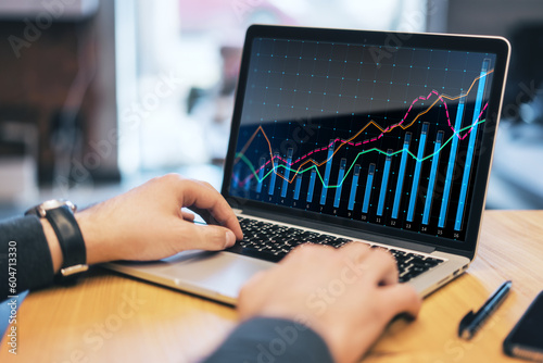 Close up of male hands using laptop keyboard on desk with growing business chart grid and other items. Corporate growth plan and company development concept.