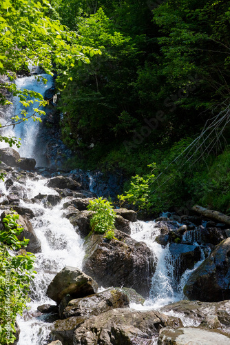 Hidden rain forest waterfall with lush foliage and mossy rocks.Tropical sunny landscape - fresh summer high waterfall in jungle with lush green foliage.Waterfall in the deep forest valley
