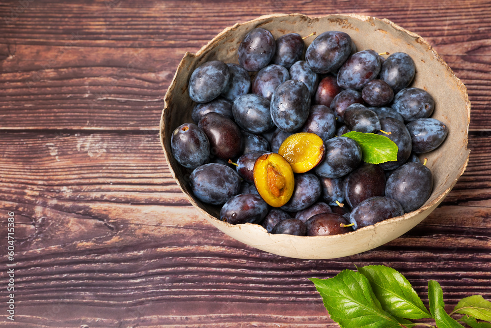 A rustic bowl full of freshly harvested plums A rustic bowl full of freshly harvested plums