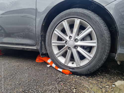 the car is parked with wheels on the barrier cones.
