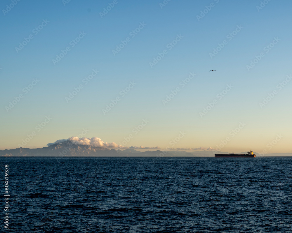 Ship passing in front of mountains with clouds above