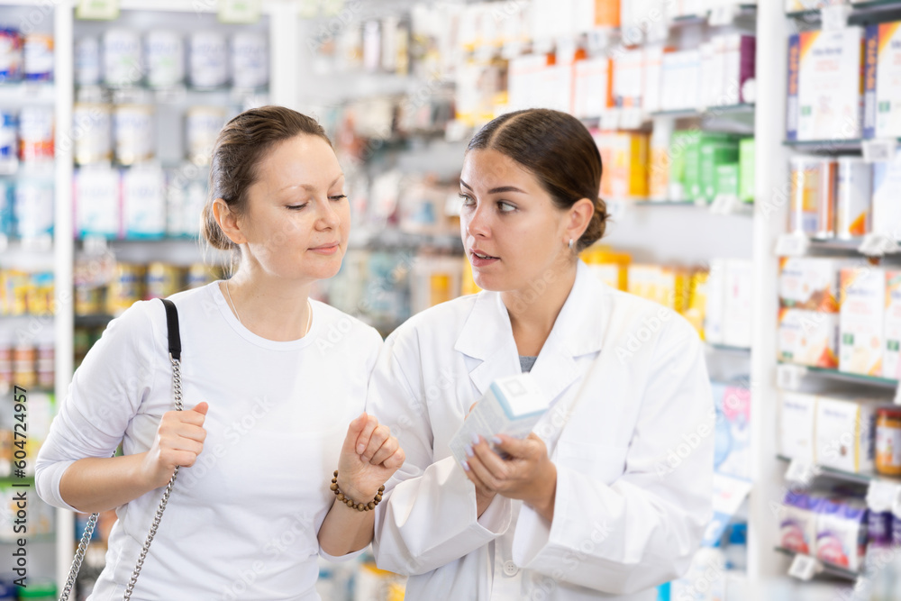 Woman pharmacist gives advice to woman customer what drug to buy in pharmacy