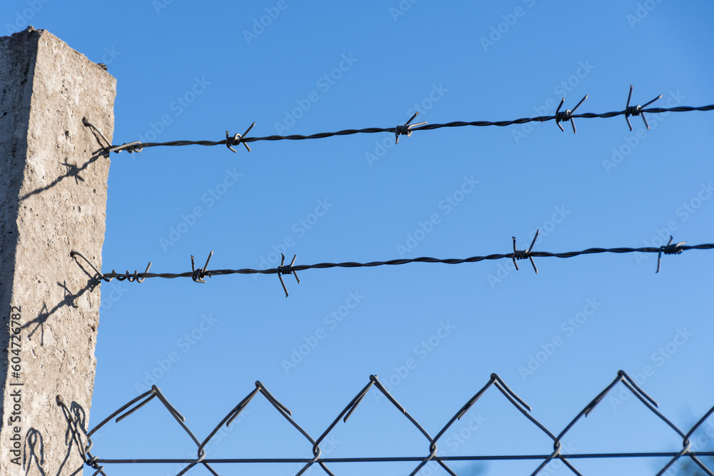 Barbed wire fence connected to a column. Barbed wire fence connected to a column.