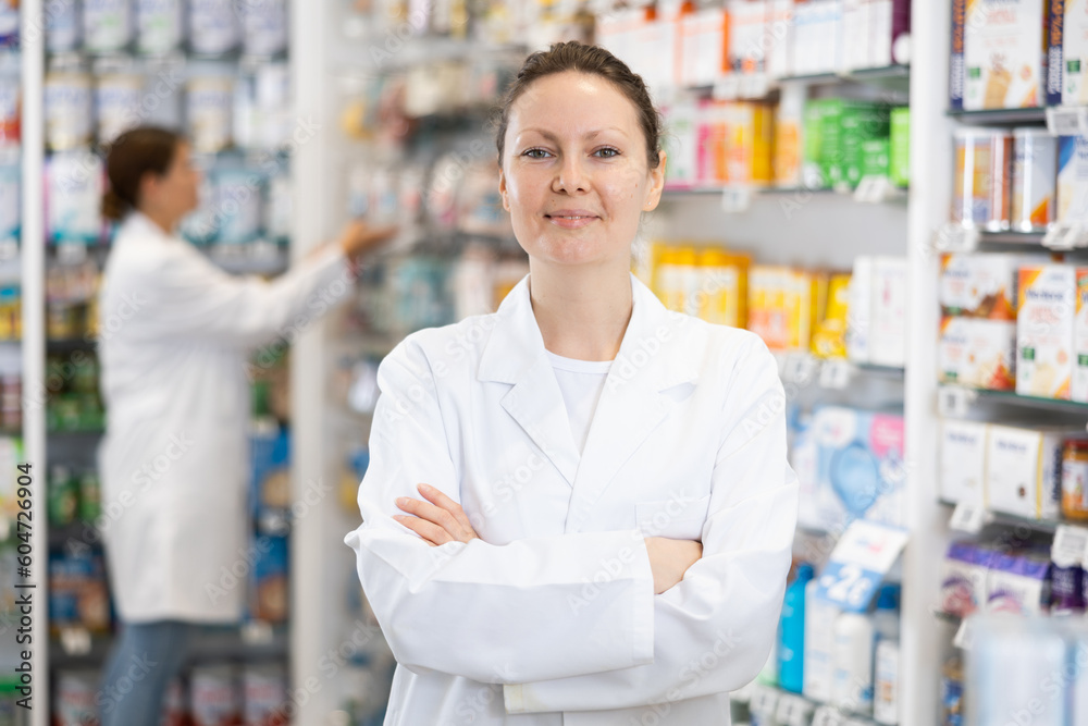 Portrait of friendly smiling female pharmacist in interior of pharmacy or a store selling healing cosmetics