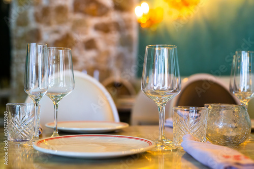 Elegant glasses and decorated plates on the wooden table at the restaurant