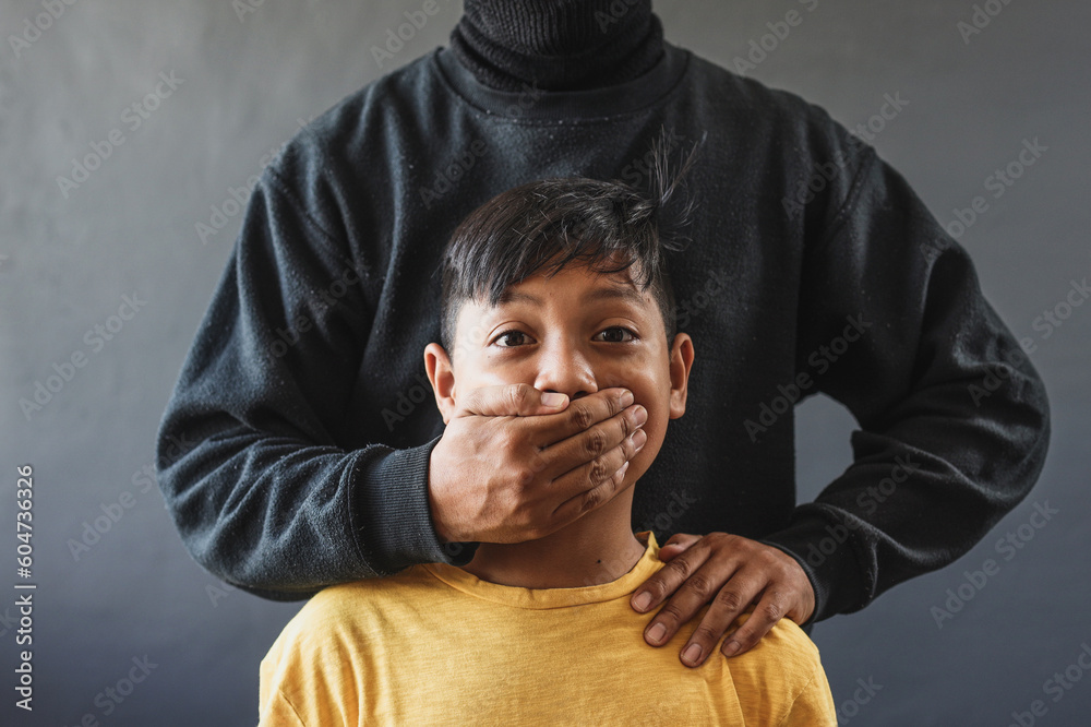 Foto de Adult man covering scared little boy's mouth, holds him hostage